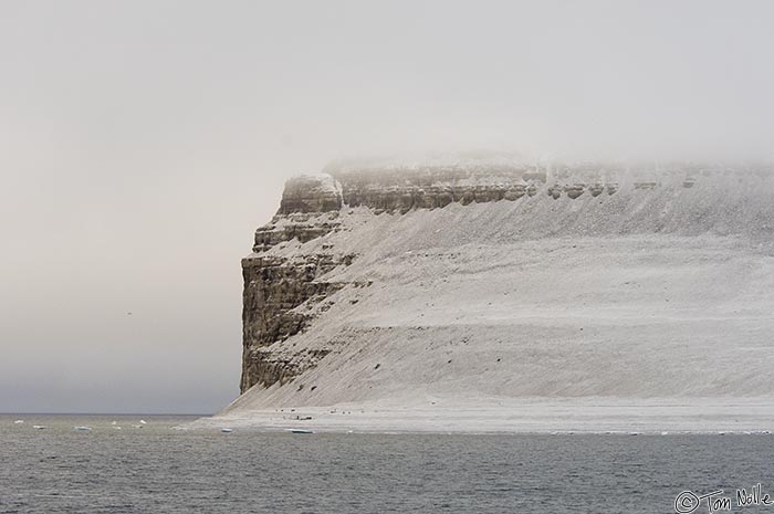 ArcticQ_20080827_071444_474_2X.jpg - The small set of ruins in a line from the right edge of the visible cliff face is the winter-over site of the Franklin Expedition, the last known location of the party before they were lost in search of the Northwest Passage in 1846.  Beechy Island, Nunavut, Canada.