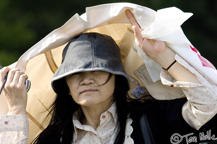 Japan_20080425_021622_413_2X.jpg - A woman shields herself against a hot sun using her jacket.  Near the Imperial Palace Tokyo, Japan.